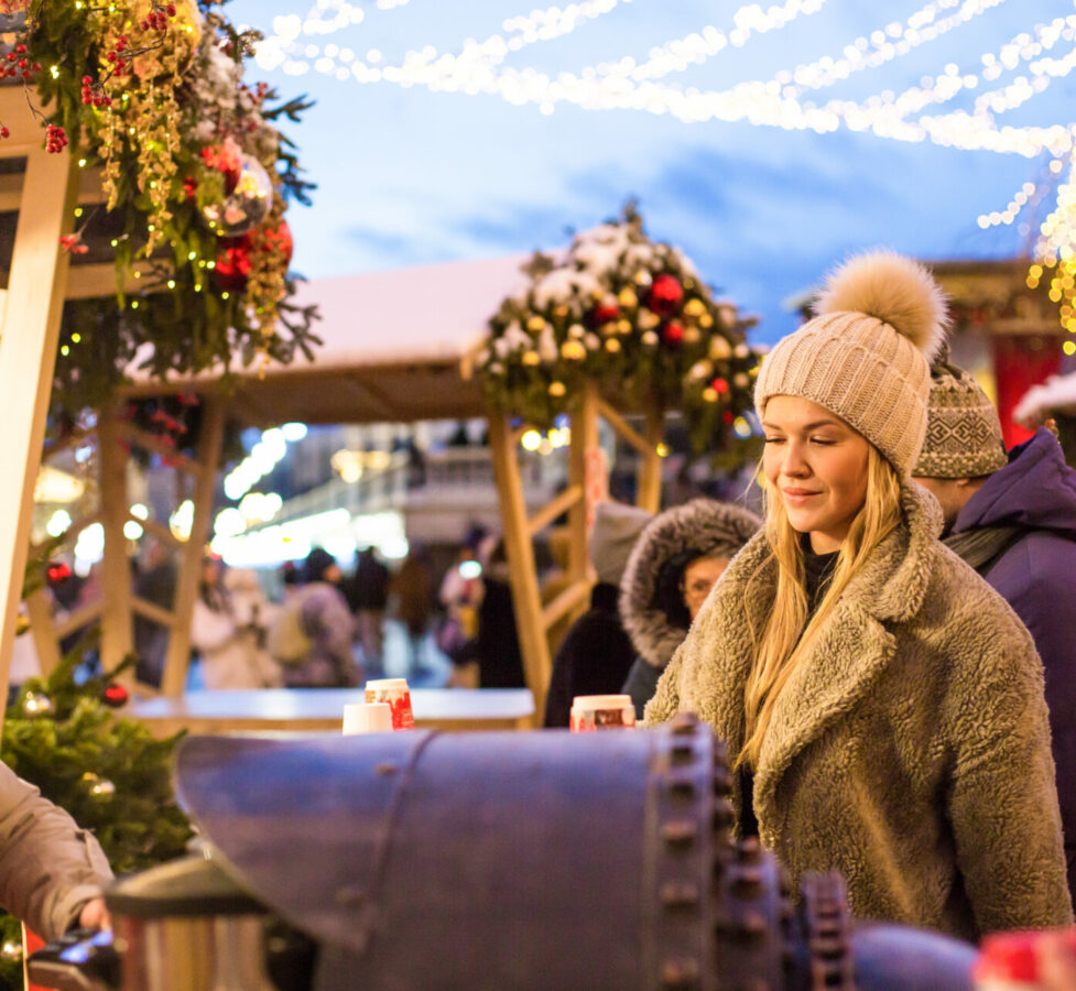 A happy smiling lady poses at a street holiday fair, holding lollipops in her hands. High quality photo